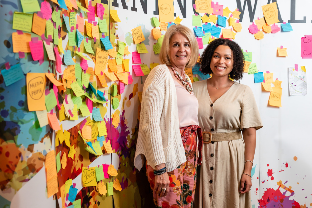 two-women-standing-smiling-tanarack-learning-wall-diversity two-women-standing-smiling-tanarack-learning-wall-diversity